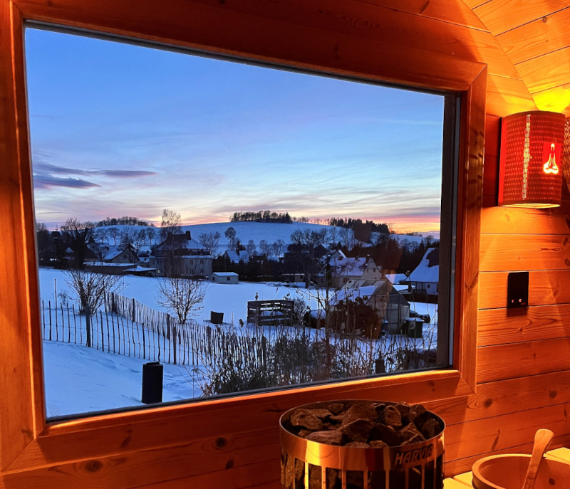 Rückwandfenster mit Panoramablick auf die verschneite Abendlandschaft, warm beleuchteter Innenraum