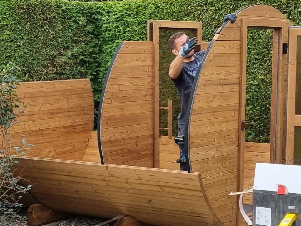 Monteur beim Zusammensetzen einer Oval-Sauna im Garten